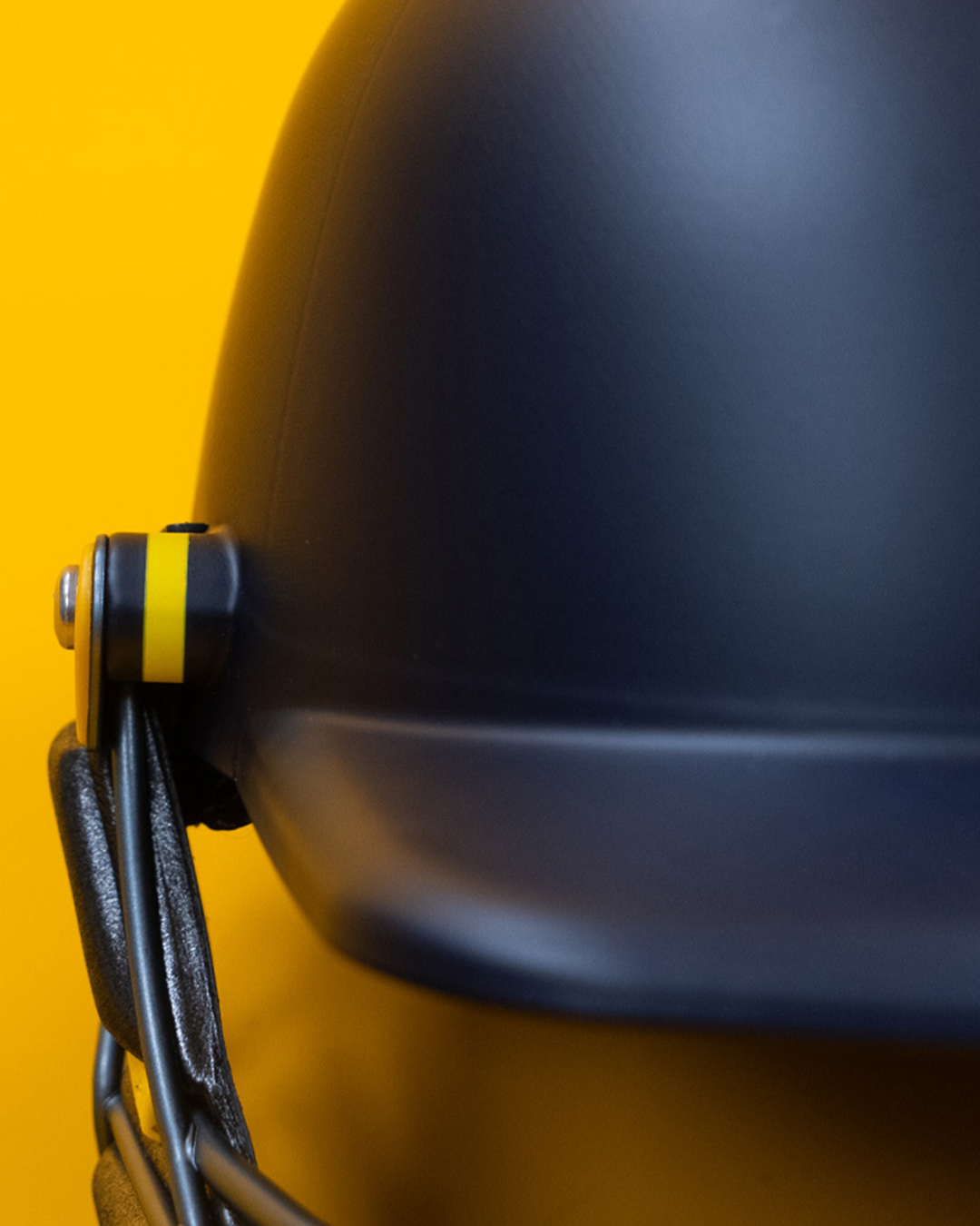 Close-up detail of the Masuri E Line Player Steel navy cricket helmet, showing the side grille clip and matte painted shell
