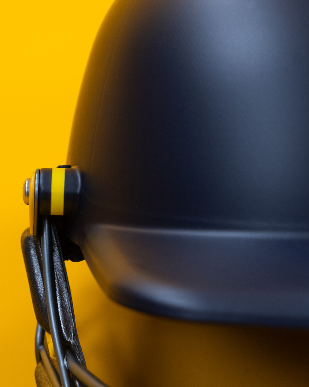 Close-up of the peak adjustment clip on the Masuri E Line Player Titanium navy cricket helmet, fitted with StemGuard Lite 2.0 neck protection