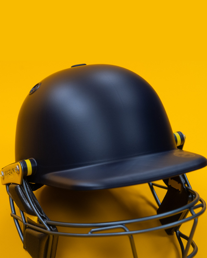 Rear view of the Masuri E Line Player Titanium navy cricket helmet showing the peak and shell, fitted with StemGuard Lite 2.0 neck protection